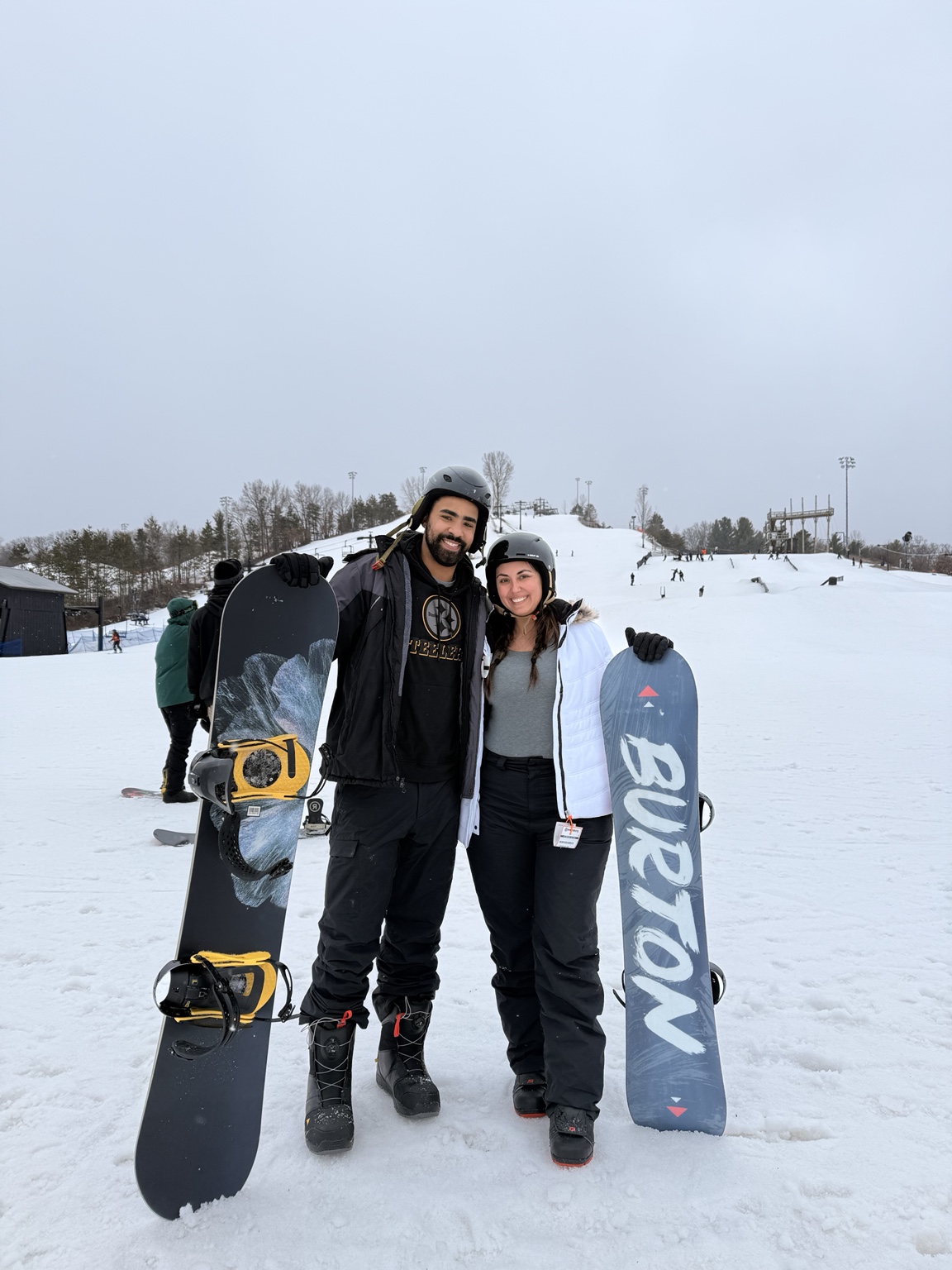 Two snowboarders holding their boards on a snowy slope