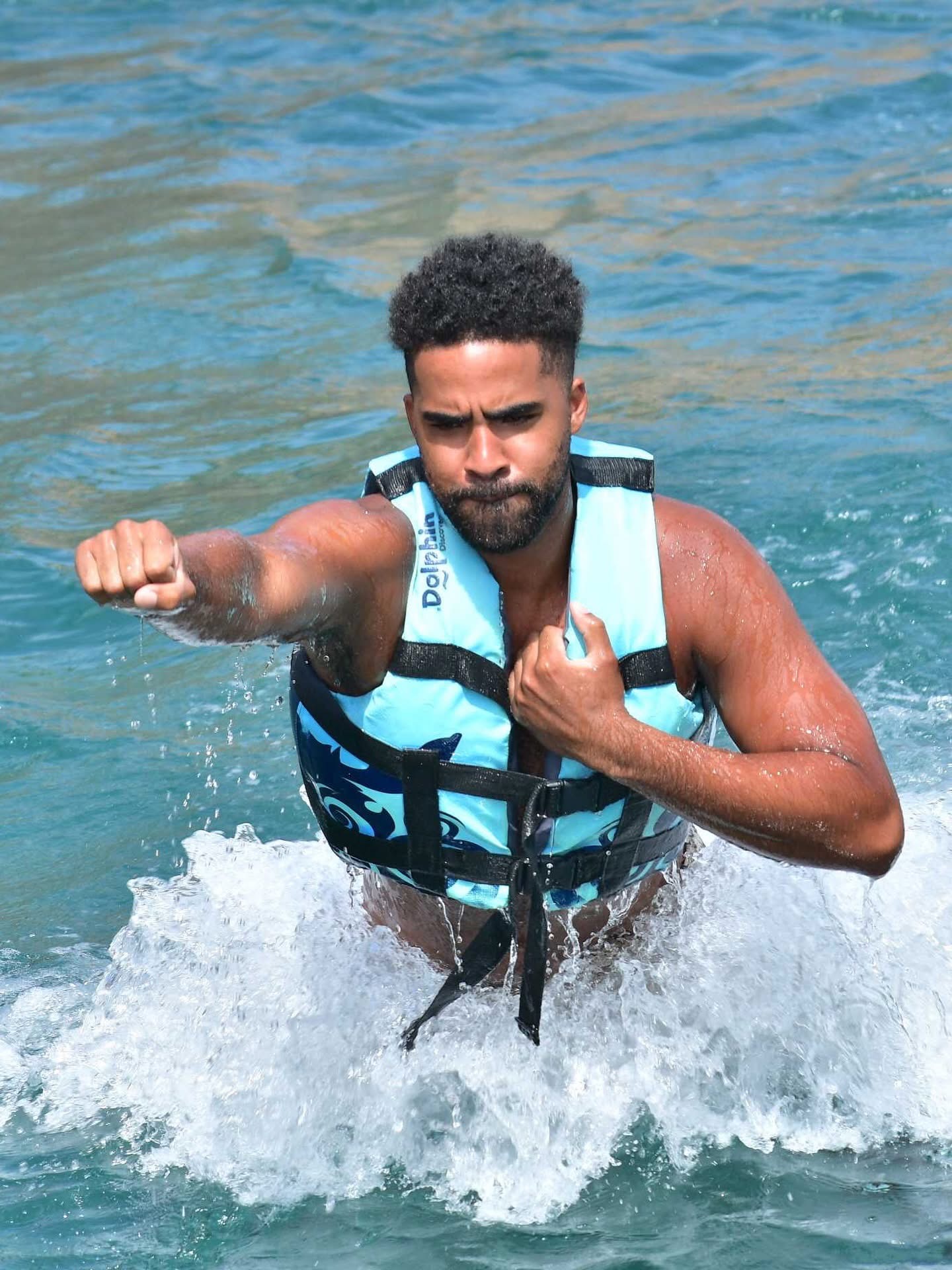 Man wearing a blue life jacket splashing through the water